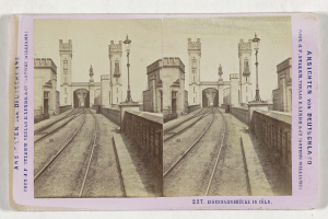 Schwarz-weißes stereoskopisches Bild einer Bahntrasse mit der Eisenbahnbrücke in Köln, Deutschland, das Bahnschienen, Wände, Pfosten, Statuen, Himmel und Text zeigt.