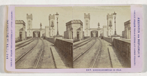 Schwarz-weißes stereoskopisches Bild einer Bahntrasse mit der Eisenbahnbrücke in Köln, Deutschland, das Bahnschienen, Wände, Pfosten, Statuen, Himmel und Text zeigt.