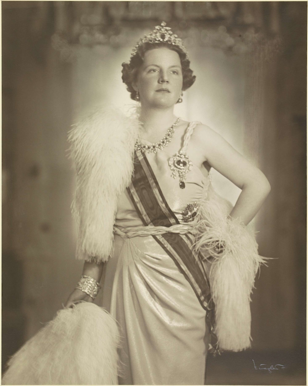 Schwarzes und weißes Foto der Queen Elizabeth II in einem Kleid und einer Krone mit unscharfem Hintergrund und Text unten.