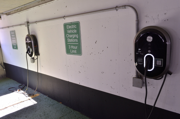 Elektrofahrzeug-Ladestationen an einer Wand in einer Tiefgarage, mit Informationsschildern darunter.