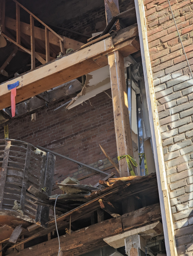 Teilweise abgerissener Bau mit verstreuten Trümmern, zerbrochenen Fenstern und Türen.