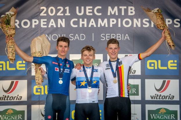 Drei medaillenreiche Männer auf einem Podest bei den 2021 UEC MTB Europameisterschaften, jeder hält einen Blumenstrauß.