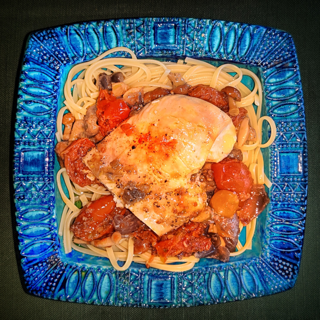 Ein blaues Teller mit Spaghetti und Hühnerjagd, das eine großzügige Portion Spaghetti, saftiges Huhn und eine reichhaltige Tomatensoße enthält.