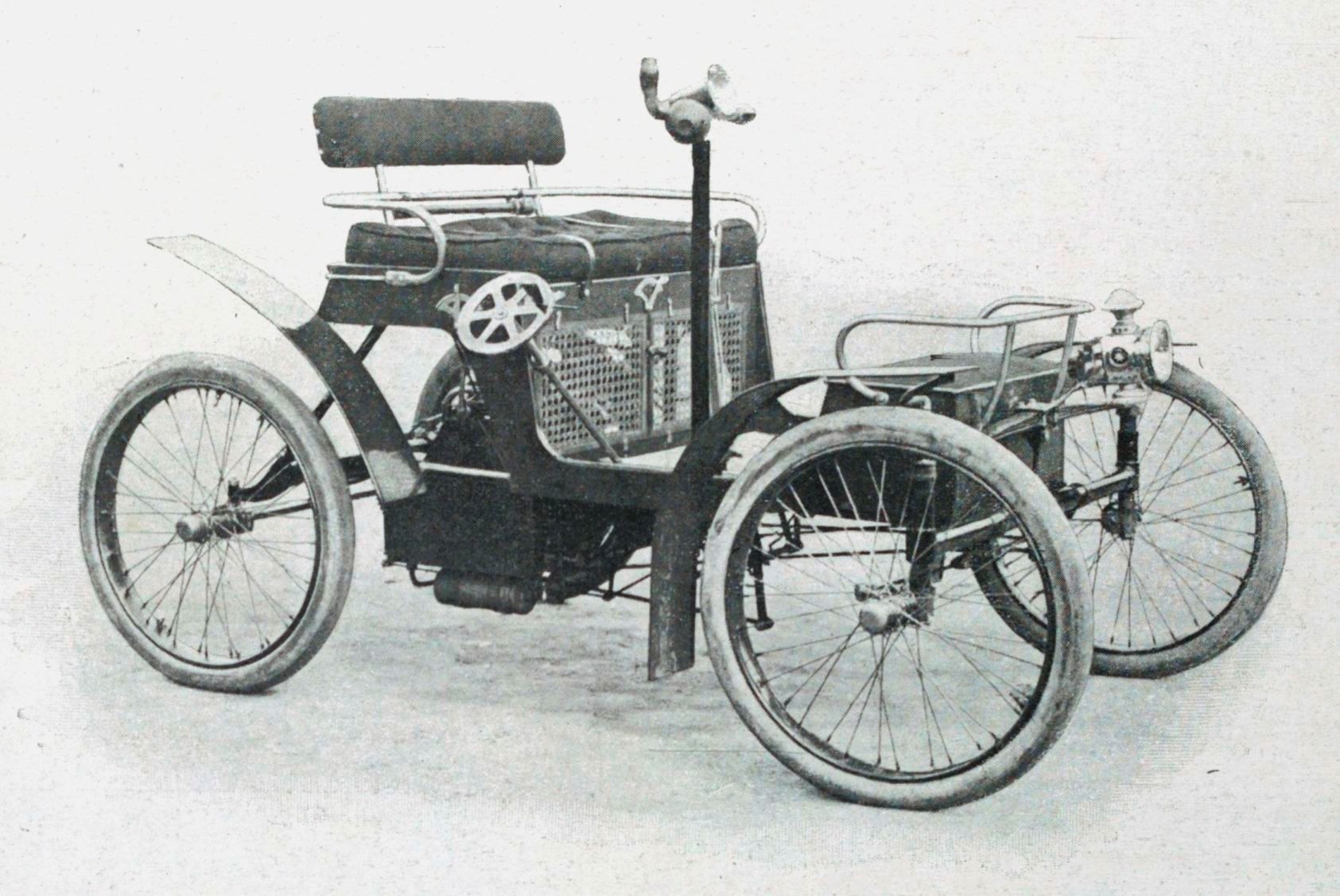 Vintage-Schwarzweiß-Foto eines frühen 1900er-Elektroautos mit schlankem, aerodynamischem Design, großem runden Scheinwerfer, geschwungener Dachlinie, vier großen Rädern, prominentem Heckmotor, leichtem Polsterbezug und Armaturenbrett mit mehreren Knöpfen und Drehreglern.