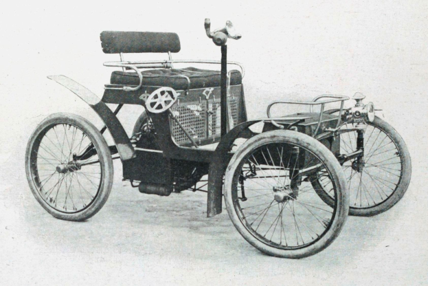 Vintage-Schwarzweiß-Foto eines frühen 1900er-Elektroautos mit schlankem, aerodynamischem Design, großem runden Scheinwerfer, geschwungener Dachlinie, vier großen Rädern, prominentem Heckmotor, leichtem Polsterbezug und Armaturenbrett mit mehreren Knöpfen und Drehreglern.