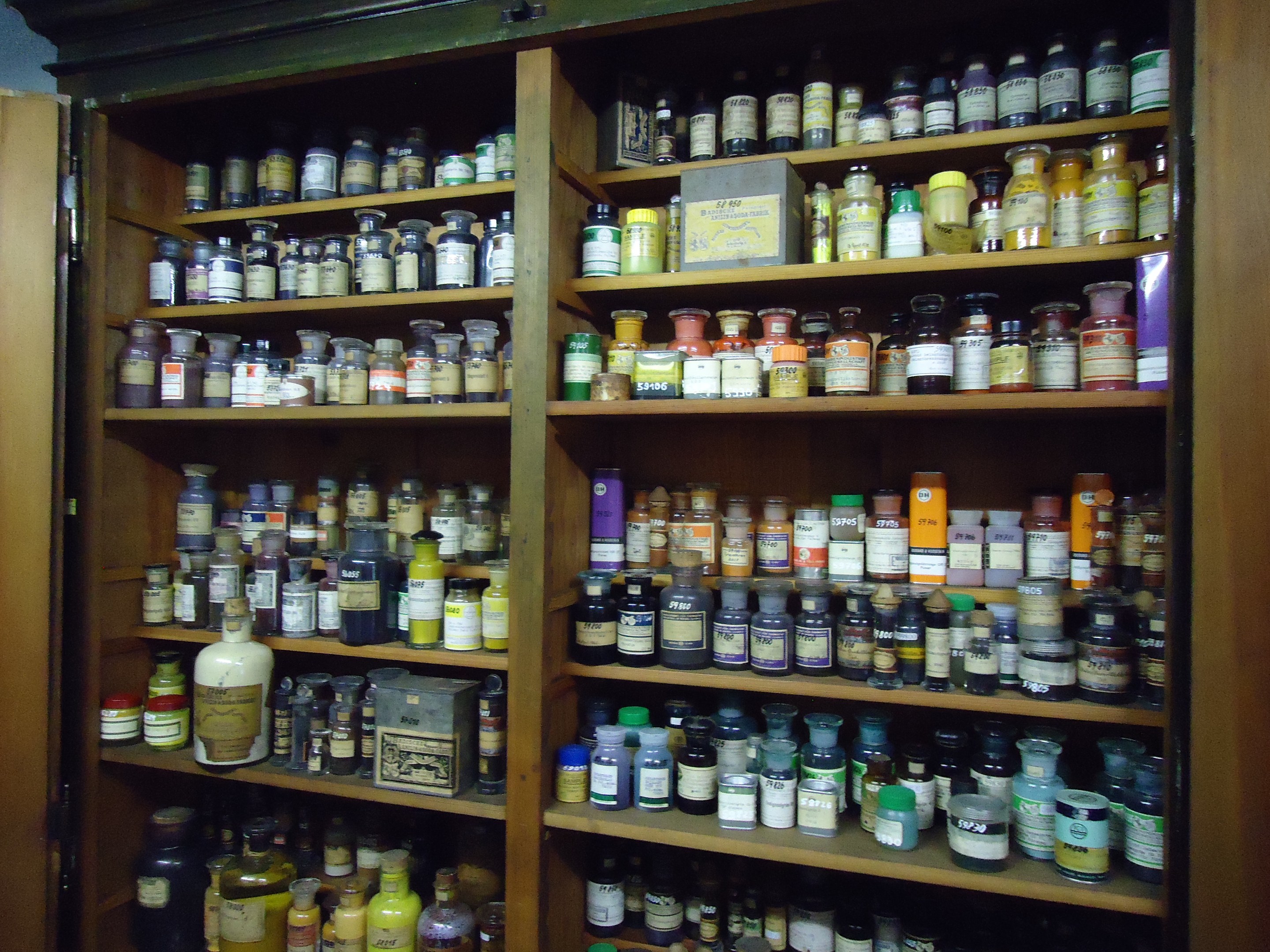 Ein hölzerner Schrank mit einer linksseitigen Tür, der ordentlich angeordnete Flaschen enthält.