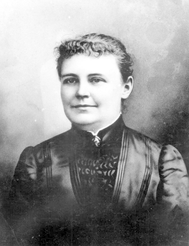 Schwarzes und weißes Foto einer Frau in einem Kleid, die mit gefalteten Händen und entschlossener Miene steht und angeblich die erste weibliche US-Präsidentin darstellt.