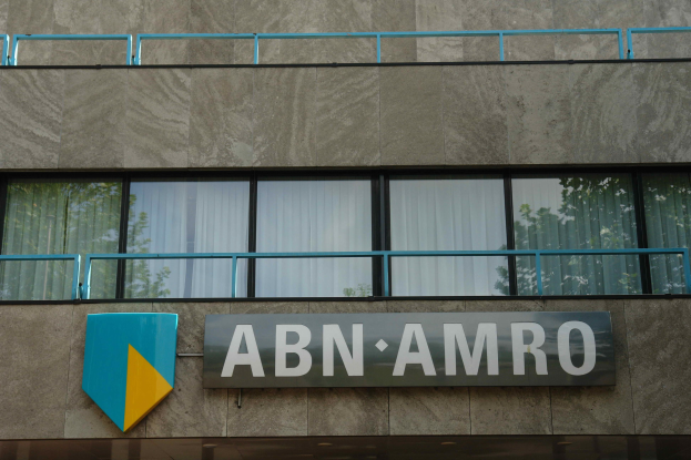 Gebäudefassade mit "ABN AMRO"-Schriftzug, ein Schild, das es als Hauptsitz angibt, Geländer und Glasfenster mit Vorhängen.