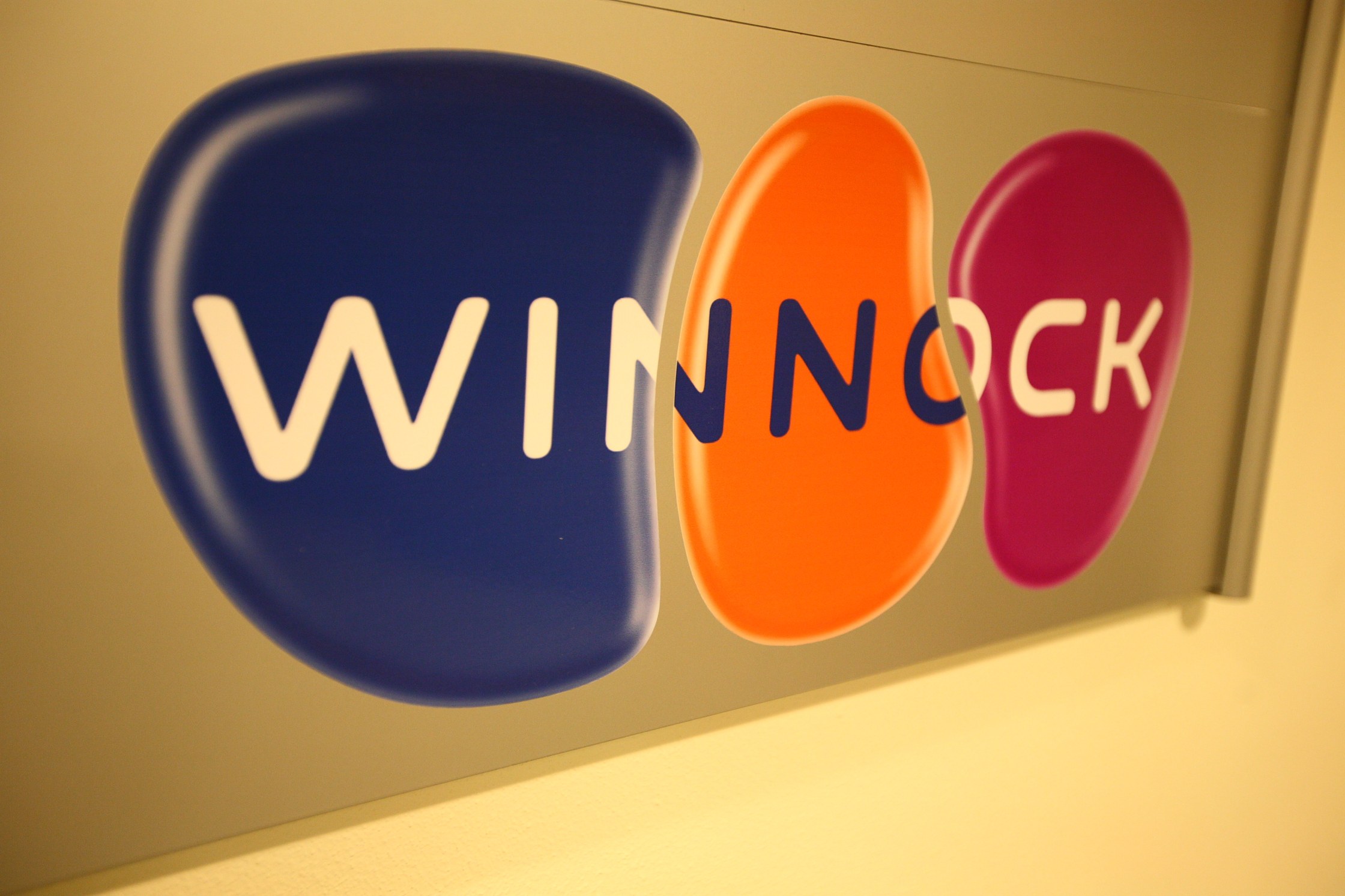 Leuchtend buntes "Winnock"-Schild an einer Wand angebracht, das einen Aktienmarkt anzeigt.