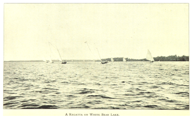 Regatta am Weißen Bärensee mit Booten auf dem Wasser, Bäumen im Hintergrund und Text unten unter einem sichtbaren Himmel.
