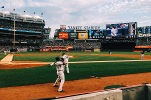 Baseballspiel im Gange im Yankee Stadium mit Spielern auf dem Feld und Zuschauern in den Rängen unter einem bewölktem Himmel.