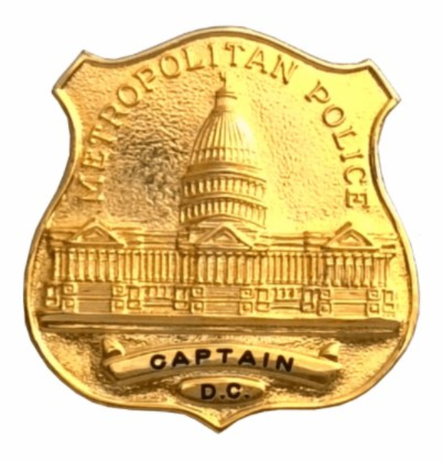Goldenes Polizeidienstabzeichen mit 'Metropolitan Police Captain' eingraviert, mittig auf weißem Hintergrund.