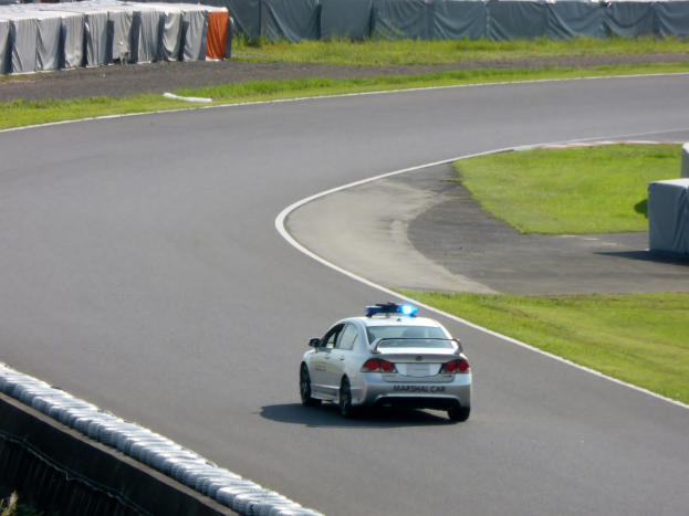 Roter Wagen mit "Rettungsgasse"-Text auf einer Straße umgeben von anderen Fahrzeugen.