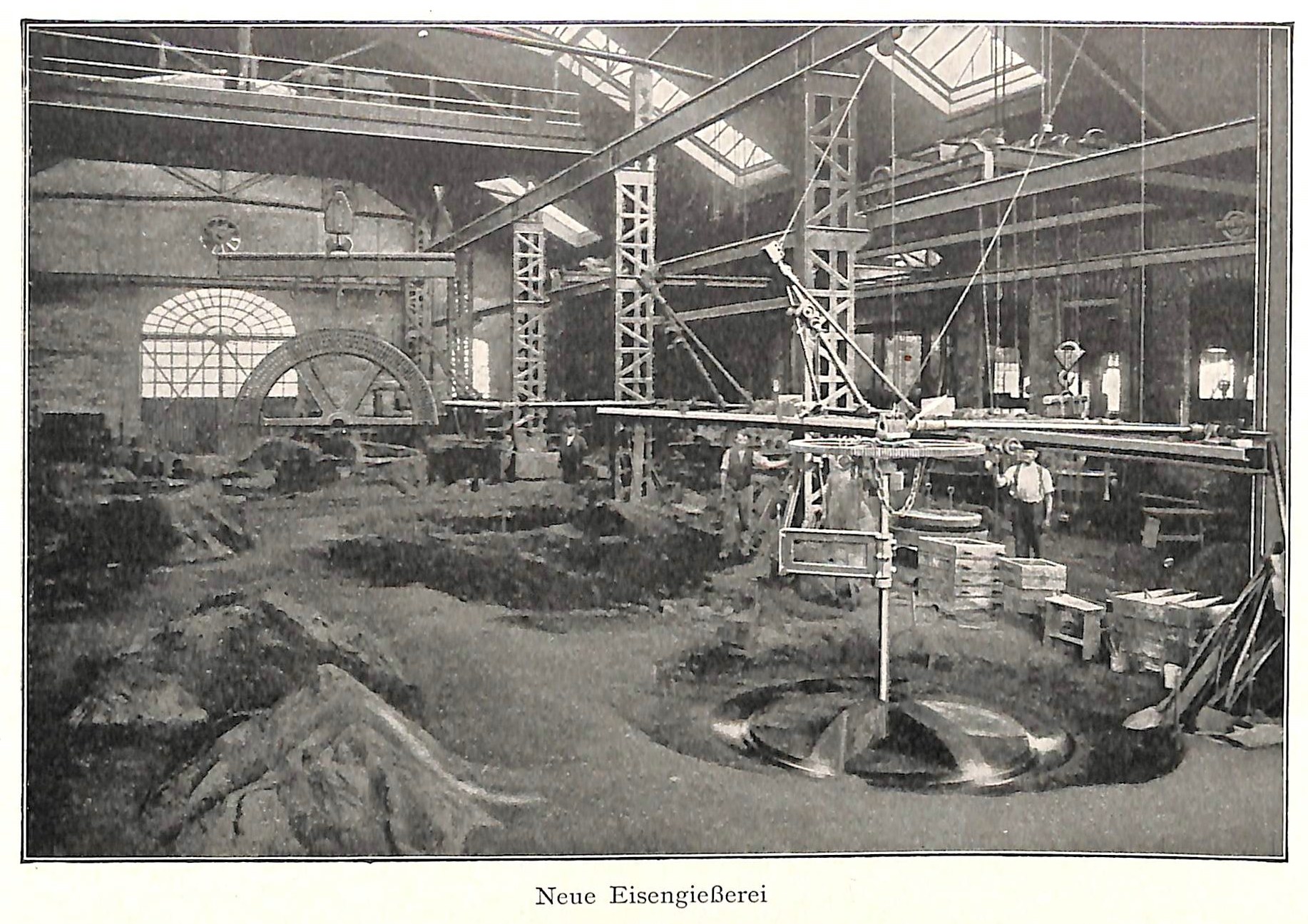 Schwarzes und weißes Foto einer historischen Fabrik mit Arbeitern, die Maschinen bedienen, umgeben von Metallstangen und -pfählen, mit der Beschriftung "Neue Eisenglebeerei, die erste Fabrik in Deutschland" unten.