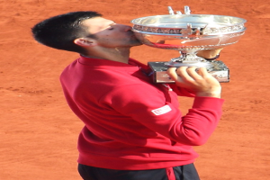 Novak Djokovic hält den French-Open-Pokal nach seinem Sieg gegen Rafael Nadal im Finale der Herren-Einzel, feiernd mit einem triumphierenden Gesichtsausdruck.