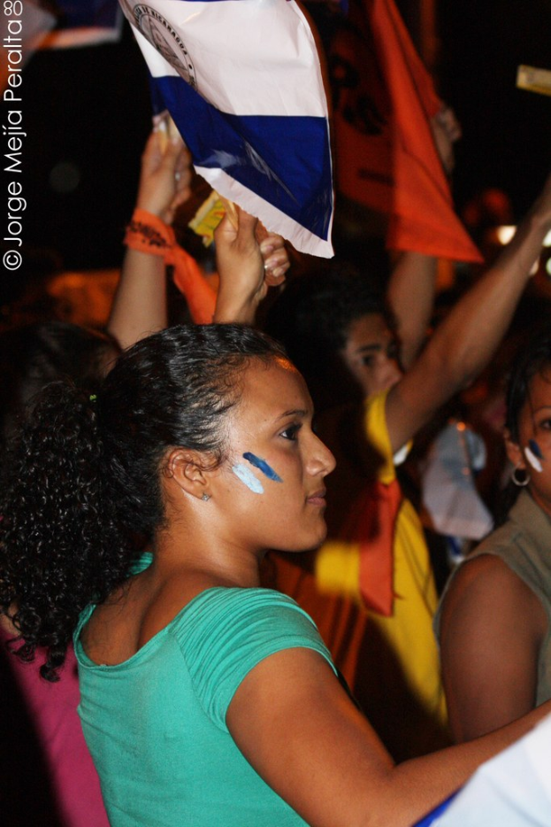 Frauen in grünen T-Shirts bei einer Demonstration, die weiße Tücher halten; viele andere Mädchen sind im Hintergrund zu sehen.