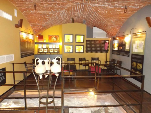 Ein Museumsraum voller Tische, Stühle, Vasen, Schilder, Wandrahmen und diversen anderen Ausstellungsstücken.