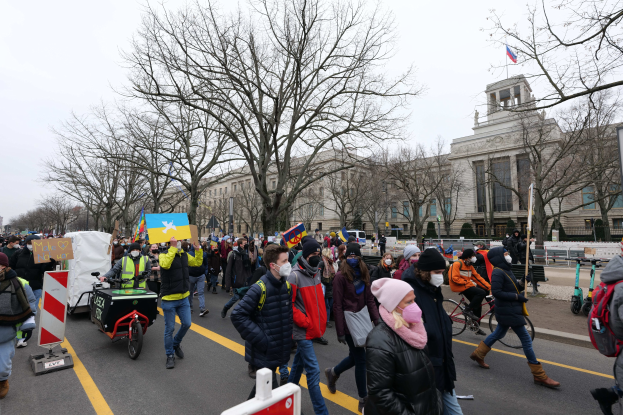 Eine große Gruppe von Menschen marschiert bei einer Demonstration in Washington, D.C. am 21. Januar 2020 mit Schildern und Fahrrädern die Straße entlang, mit Bäumen und einem klaren blauen Himmel im Hintergrund.