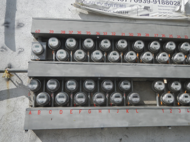 Nahaufnahme eines elektrischen Zählers an der Seite eines Gebäudes mit einem Banner mit Text über dem Zähler.