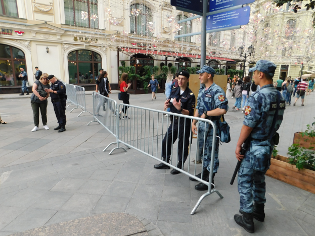 Polizisten vor einer Menschenmenge, einige mit Waffen, mit Absperrungen und Schildern im Vordergrund und Gebäuden, Laternen, Pflanzen und Bäumen im Hintergrund während eines Anti-Terror-Einsatzes in Wien, Österreich.