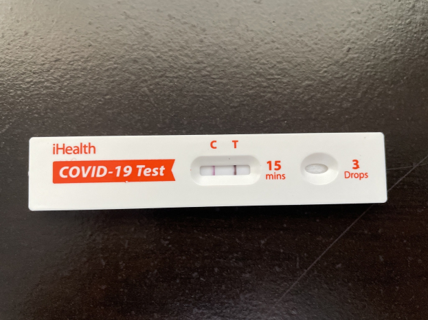 Eine schwarze Oberfl├Ąche mit einem wei├čen und roten Covid-19-Testthermometer mit Text und Zahlen.