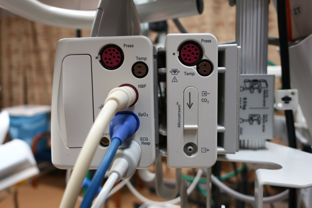 Nahaufnahme eines Beatmungsgeräts auf einem Tisch mit verschiedenen Kabeln.