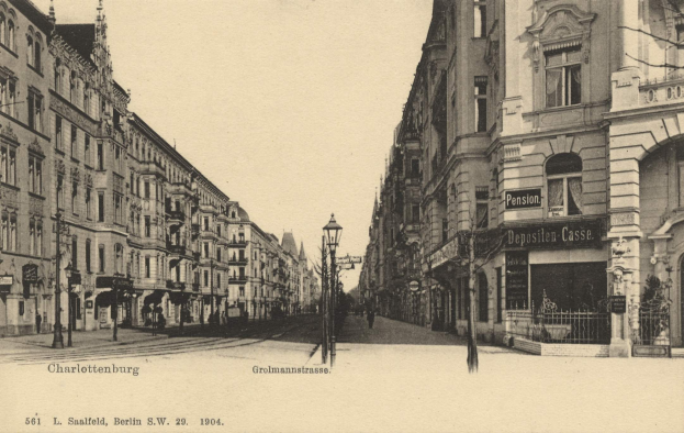 Schwarze und Weiße Straßenszene in Charlottenburg, Deutschland, mit Gebäuden, Straßenmöbeln, Fahrzeugen, Passanten und Beschilderung unter einem klaren Himmel.