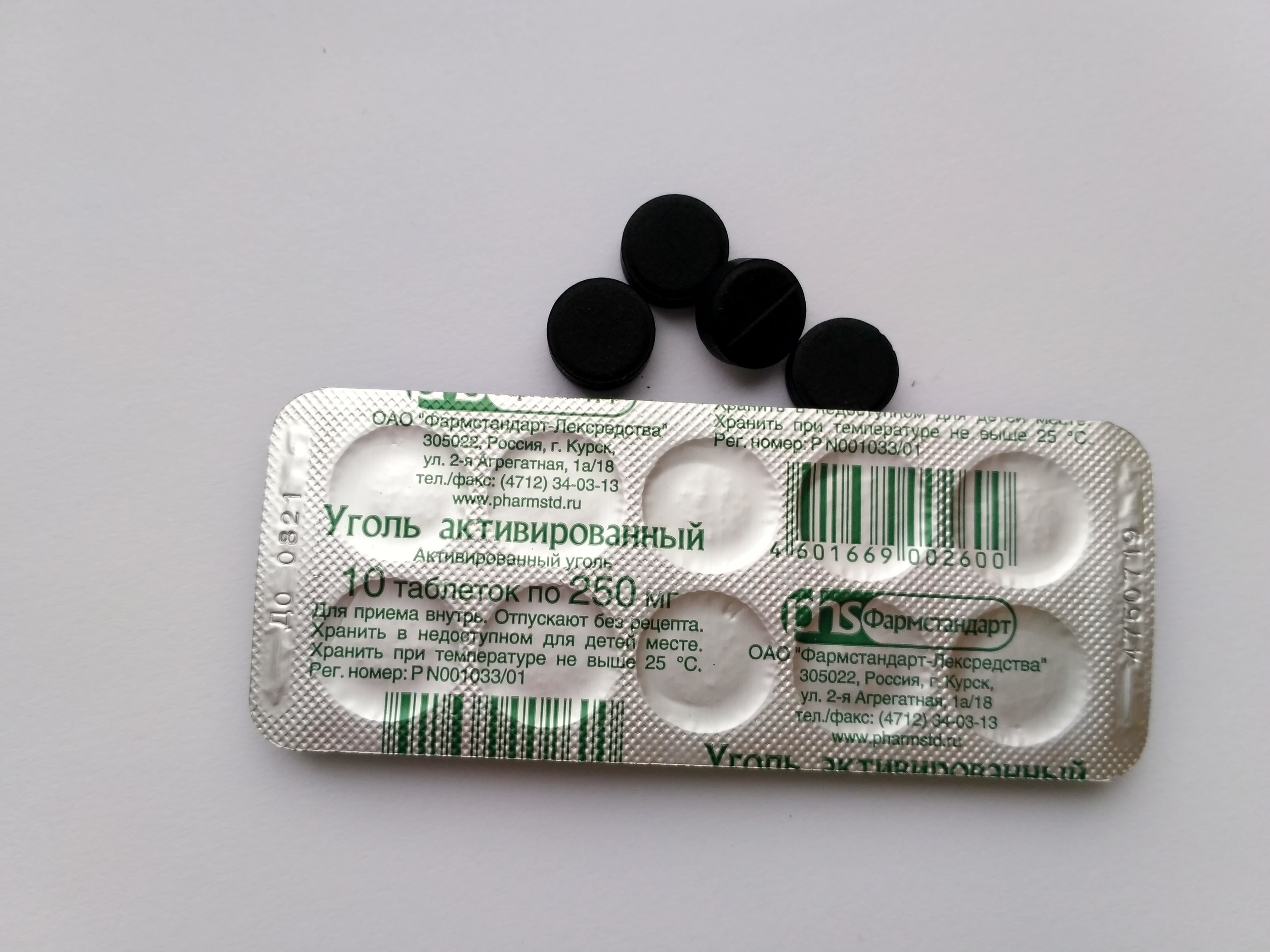 Ein weißer Tisch mit einer Blisterpackung schwarzer Pillen darauf, mit Text und einem Barcode.