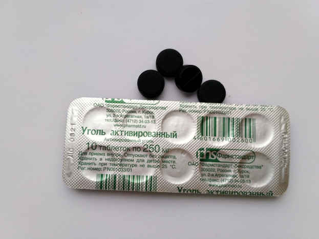 Ein weißer Tisch mit einer Blisterpackung schwarzer Pillen darauf, mit Text und einem Barcode.