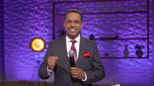 Stephen Colbert, Moderator von *The Daily Show with Trevor Noah*, steht auf einer Bühne und hält ein Mikrofon in der Hand, trägt einen Anzug, eine Krawatte und eine Brille.