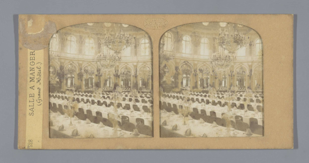Schwarz-weißes Foto eines prunkvollen Hotel-Speisesaals mit langen Tischen, Stühlen, üppigen Kronleuchtern und Fenstern an den Wänden; links zeigt ein Text die Aufschrift "Sale à Manger, Grand Hotel".