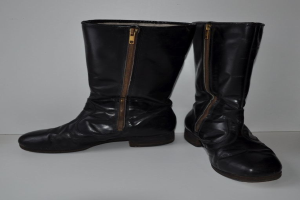 Schwarze Lederstiefel mit silbernen Reißverschlüssen auf einer weißen Oberfläche, mit einem glänzenden Finish und einem schlanken Design.