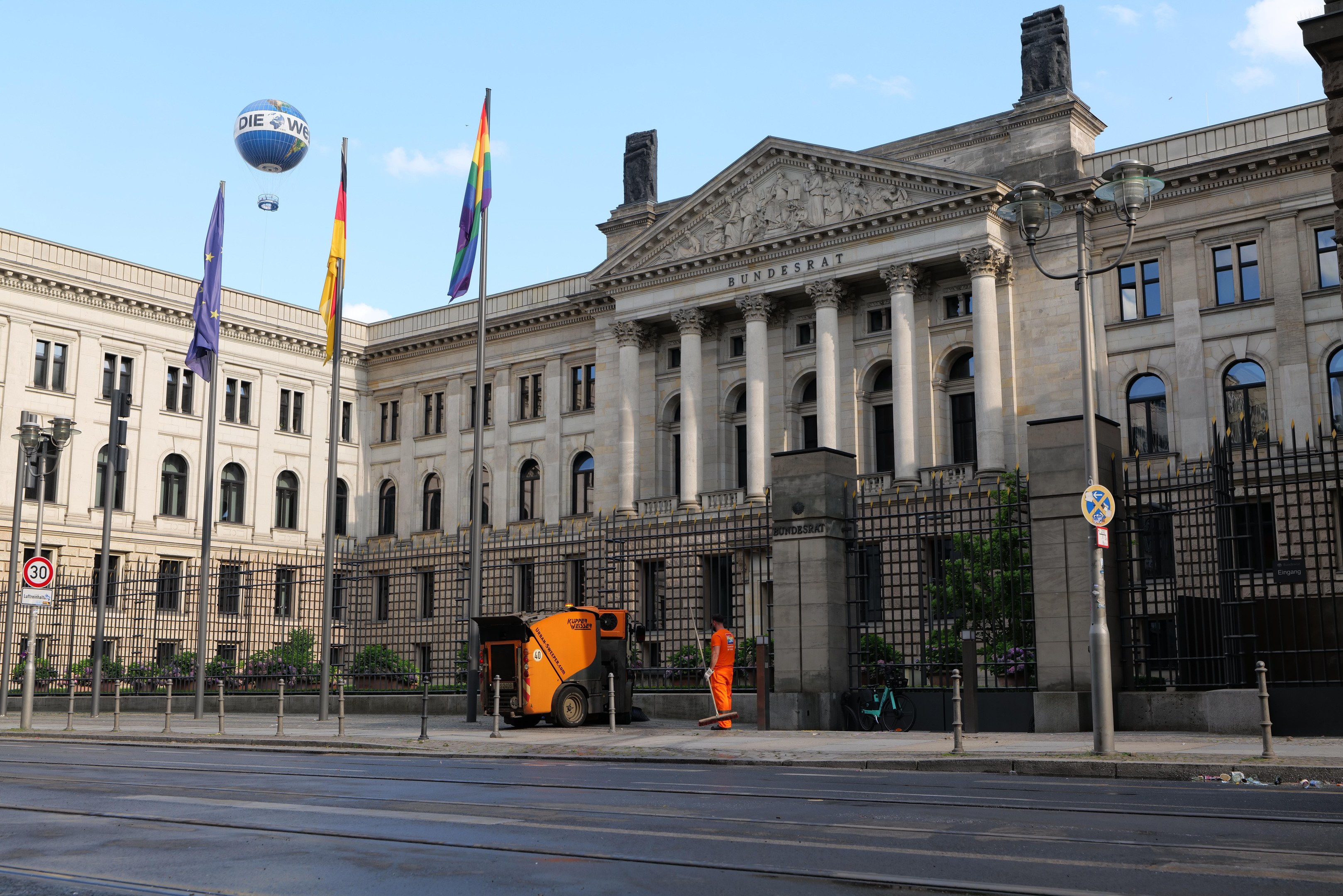 Großes modernes Gebäude mit vielen Fenstern, identifiziert als der Bundestag in Berlin, Deutschland, umgeben von Straßeninfrastruktur, Fußgängern und Bäumen unter einem bewölkten Himmel.
